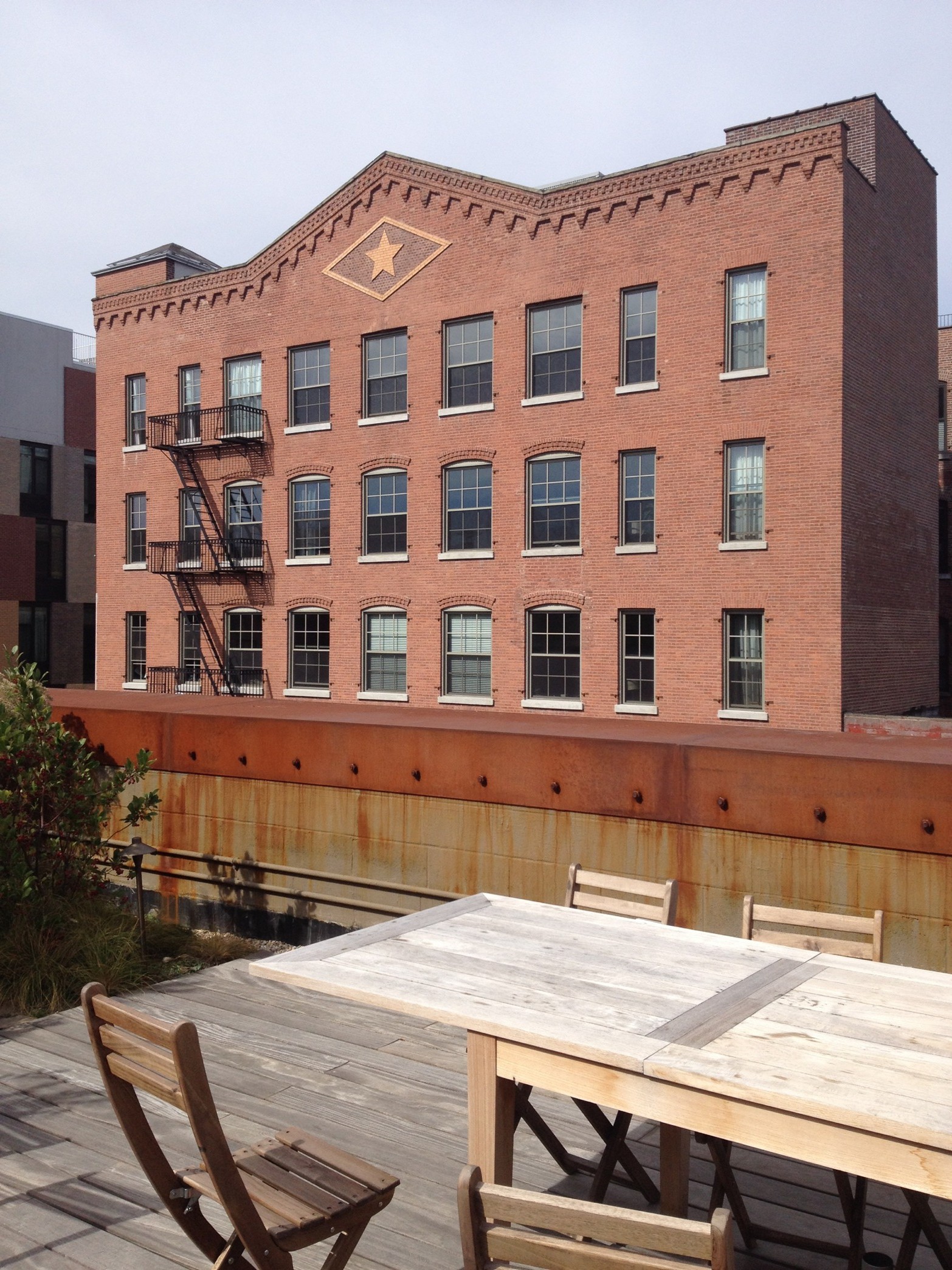 The rough corten steel beam encircles the rooftop terrace. Across the street, we can see a more traditionnal conversion of a brick building.